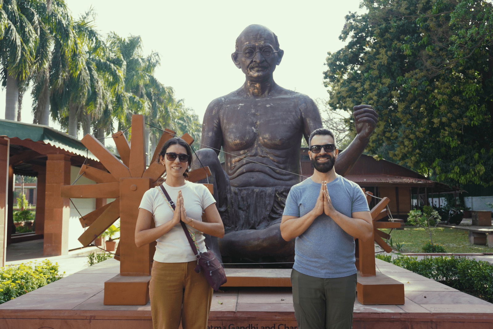 Two visitors posing in front of a statue of Mahatma Gandhi at the Gandhi Smriti memorial.