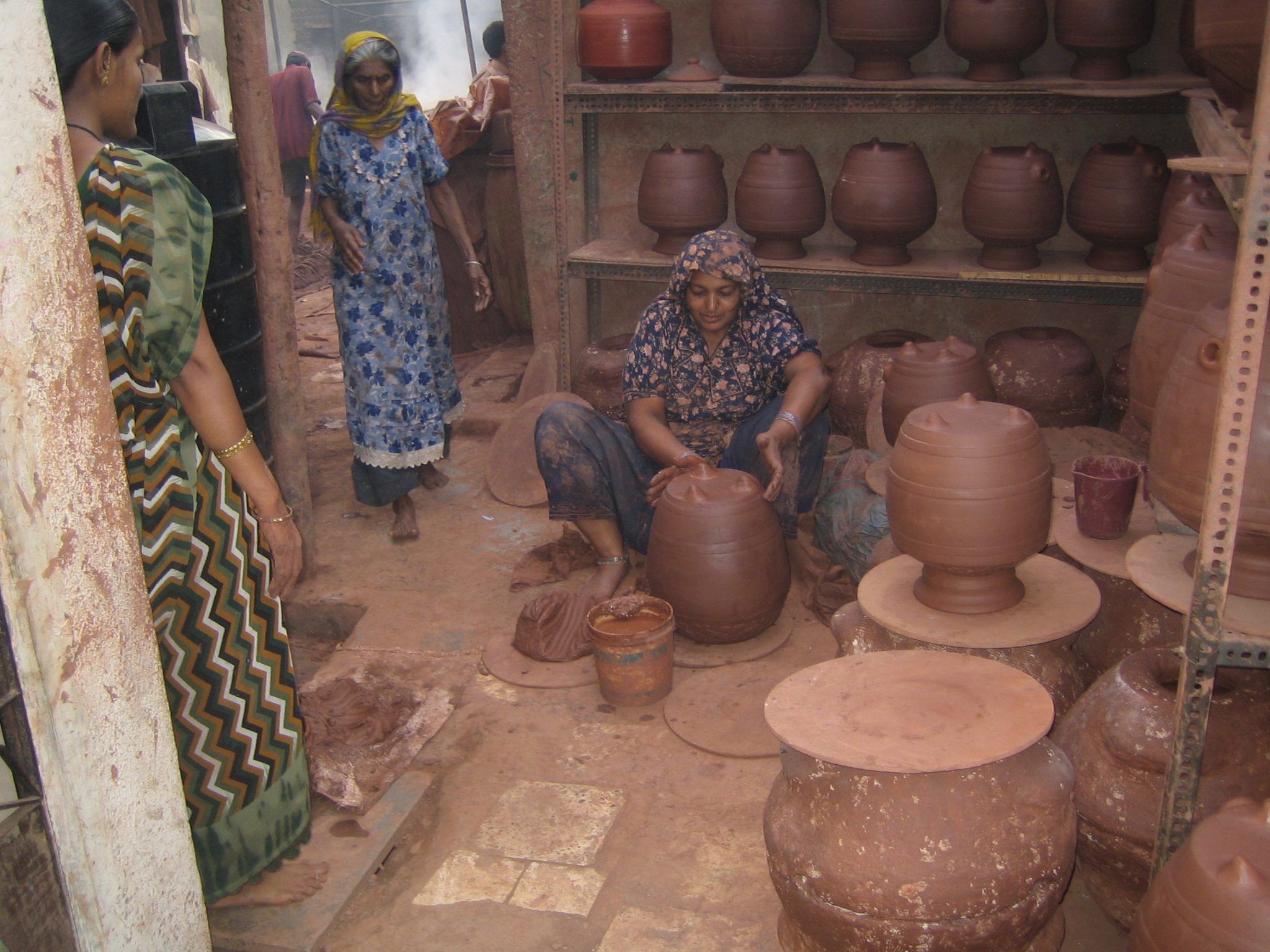 a dharavi slum women making pots in her shop to earn her living.