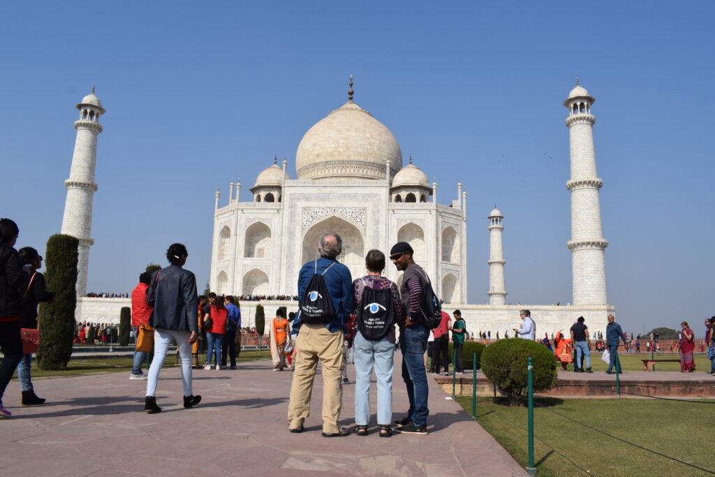 Reality tour guide with tourists at taj mahal on a golden traingle tour