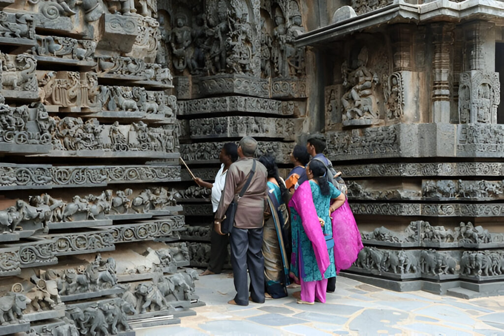 Visitors on a Golden Triangle tour admiring intricate stone carvings at a historic Indian temple during a guided cultural heritage walk.