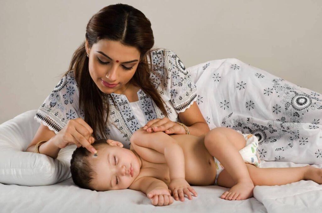 Mother applying kajal tikka on her newborn for protecting nazar (evil eye)
