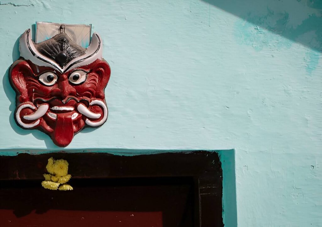 Scary evil face mask hanging on a house wall, used in India to ward off the evil eye and protect the home from negative energy.