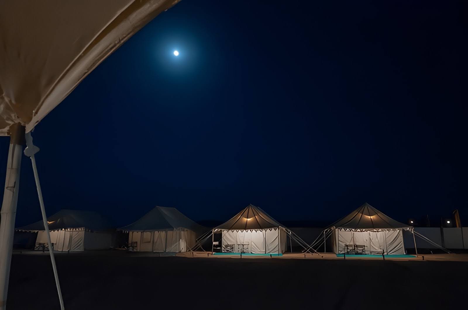 Luxury desert tents illuminated under the full moon in the Thar Desert, Rajasthan, offering an authentic cultural camping experience.
