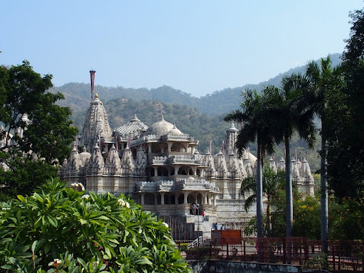 The intricate marble architecture of the Ranakpur Jain Temple surrounded by lush greenery and Aravalli hills in Rajasthan.