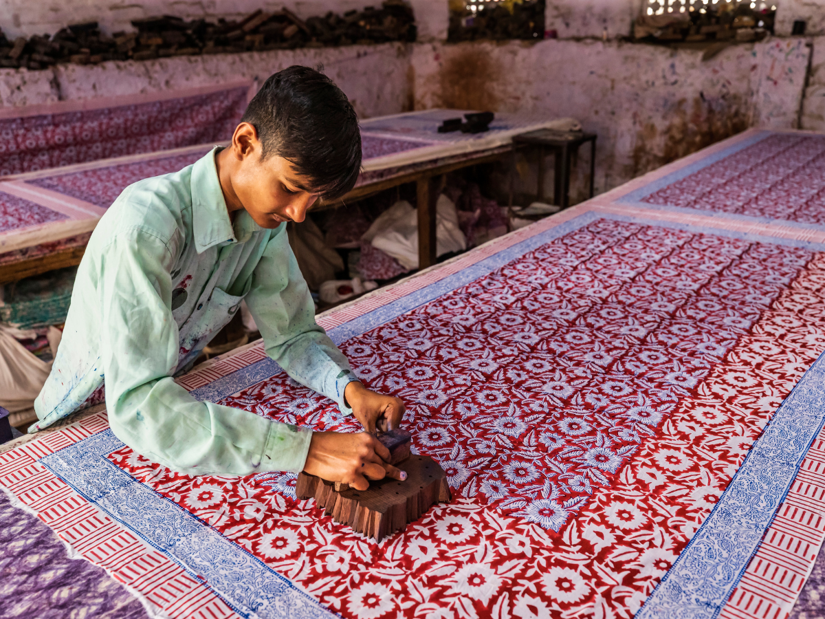 Artisan hand-printing traditional block patterns on fabric using wooden stamps during Jaipur Arts and Crafts Heritage Tour