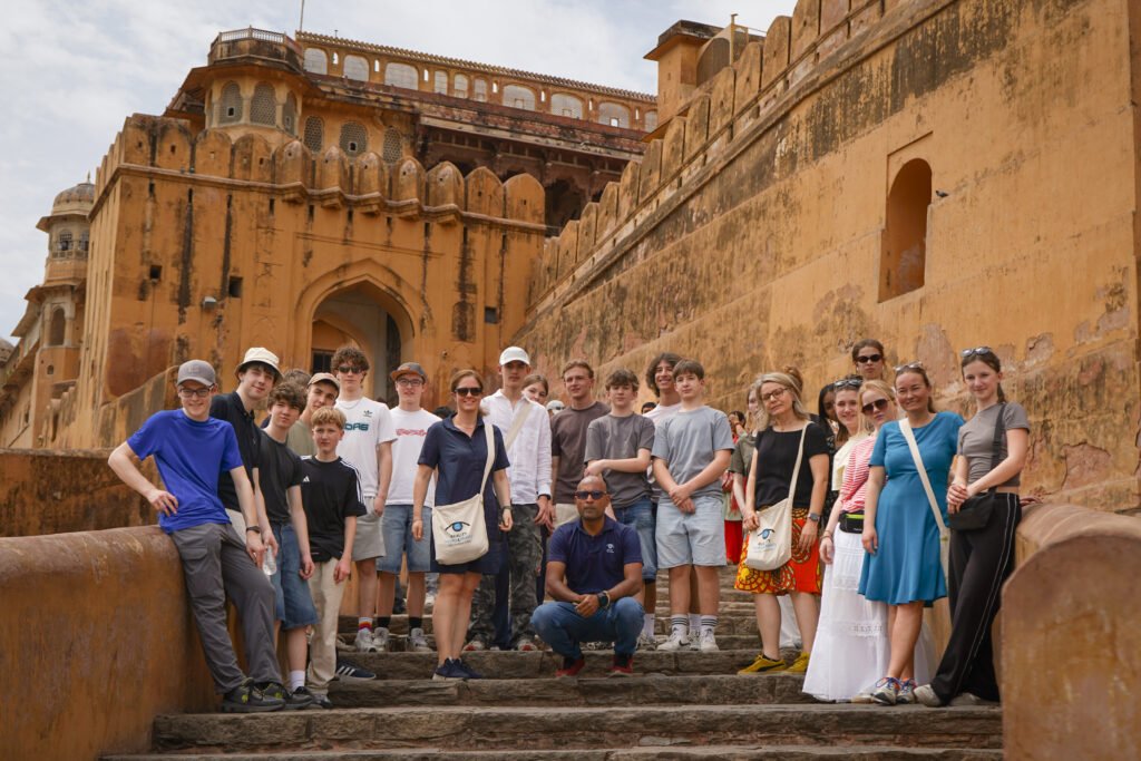 Reality Tours guide with a group of travelers on the stone steps of Amber Fort during an early morning tour in Jaipur.