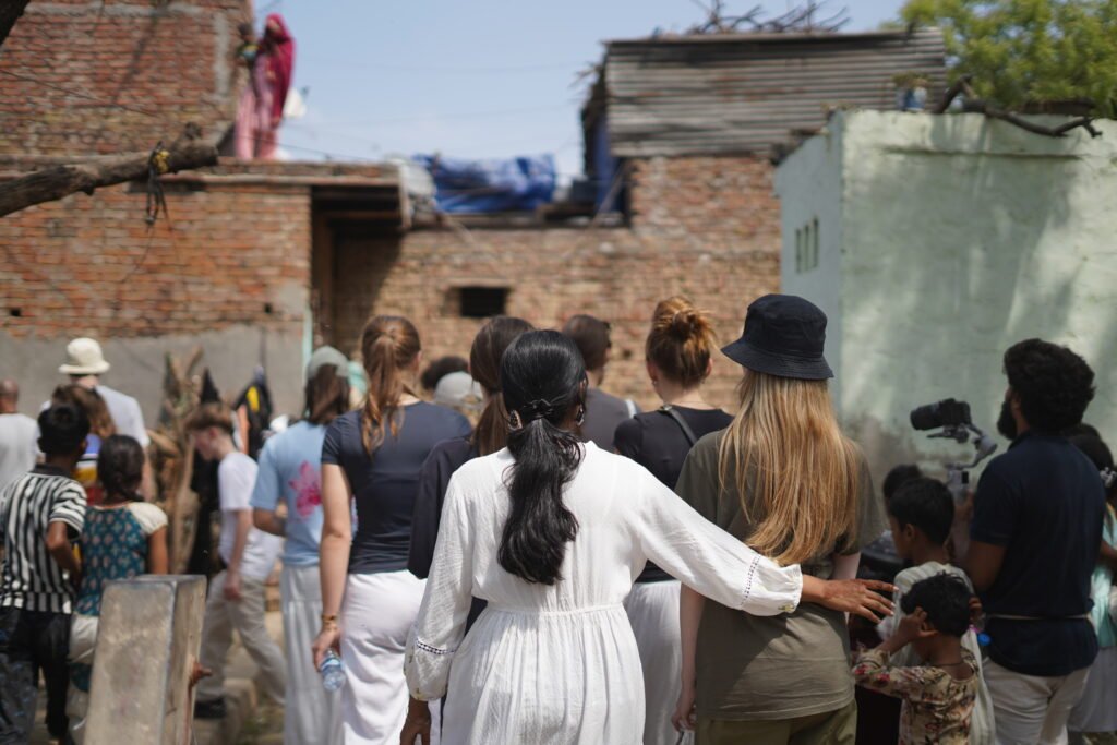 A group of tourists walking through an urban Indian neighborhood during a socially responsible guided tour.